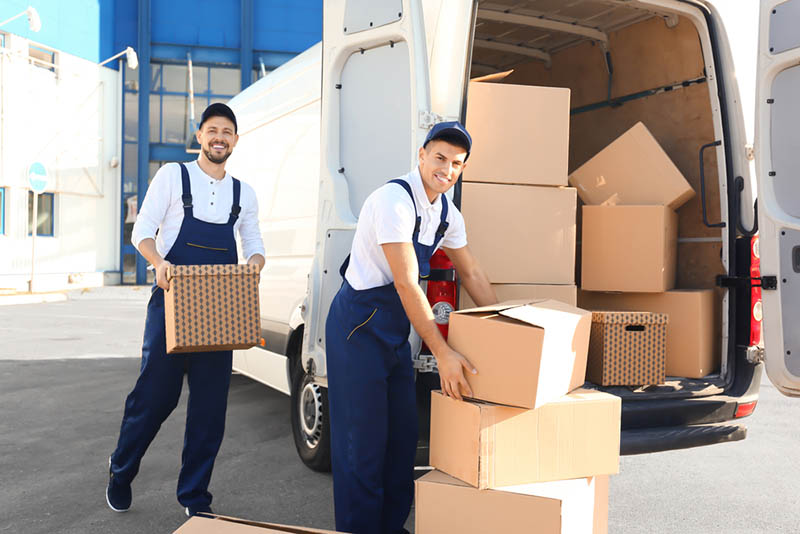 03 Dos hombres de una empresa de mudanzas cargan cajas hacia el transporte