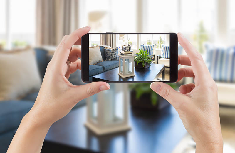 07 Manos femeninas sostienen un smartphone en modo camara para tomar una foto en el interior de una casa