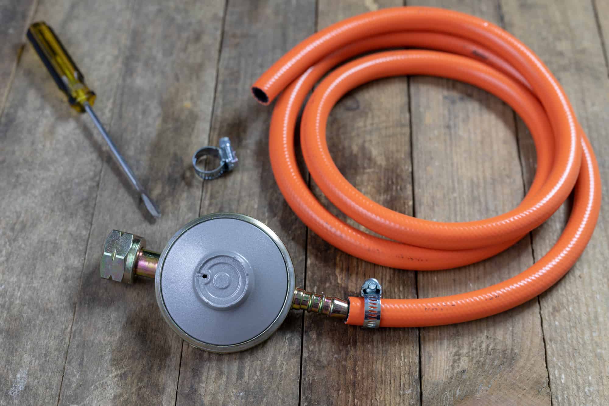 Un regulador de gas con la tuberia flexible, la presilla y el destornillador
