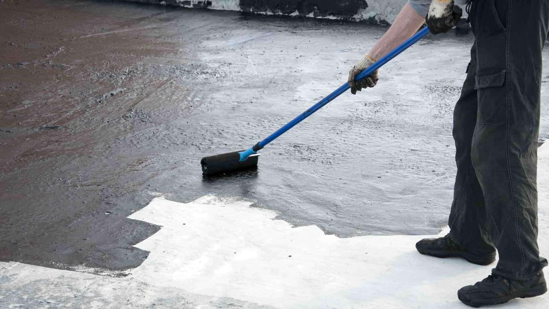 Como impermeabilizar un techo_Un trabajador pintando con impermeabilizante negro