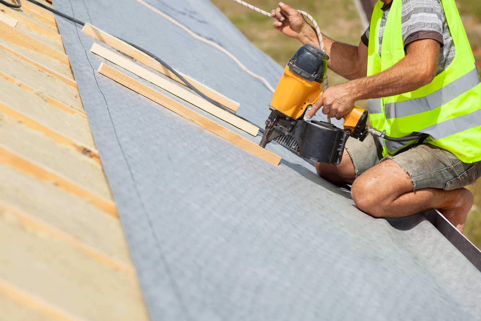 Un hombre fijando capas de material aislante termico al techo de una casa