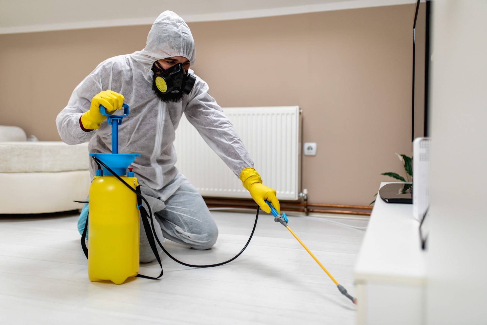 Un tecnico con traje de proteccion desinfectando el hogar con productos quimicos