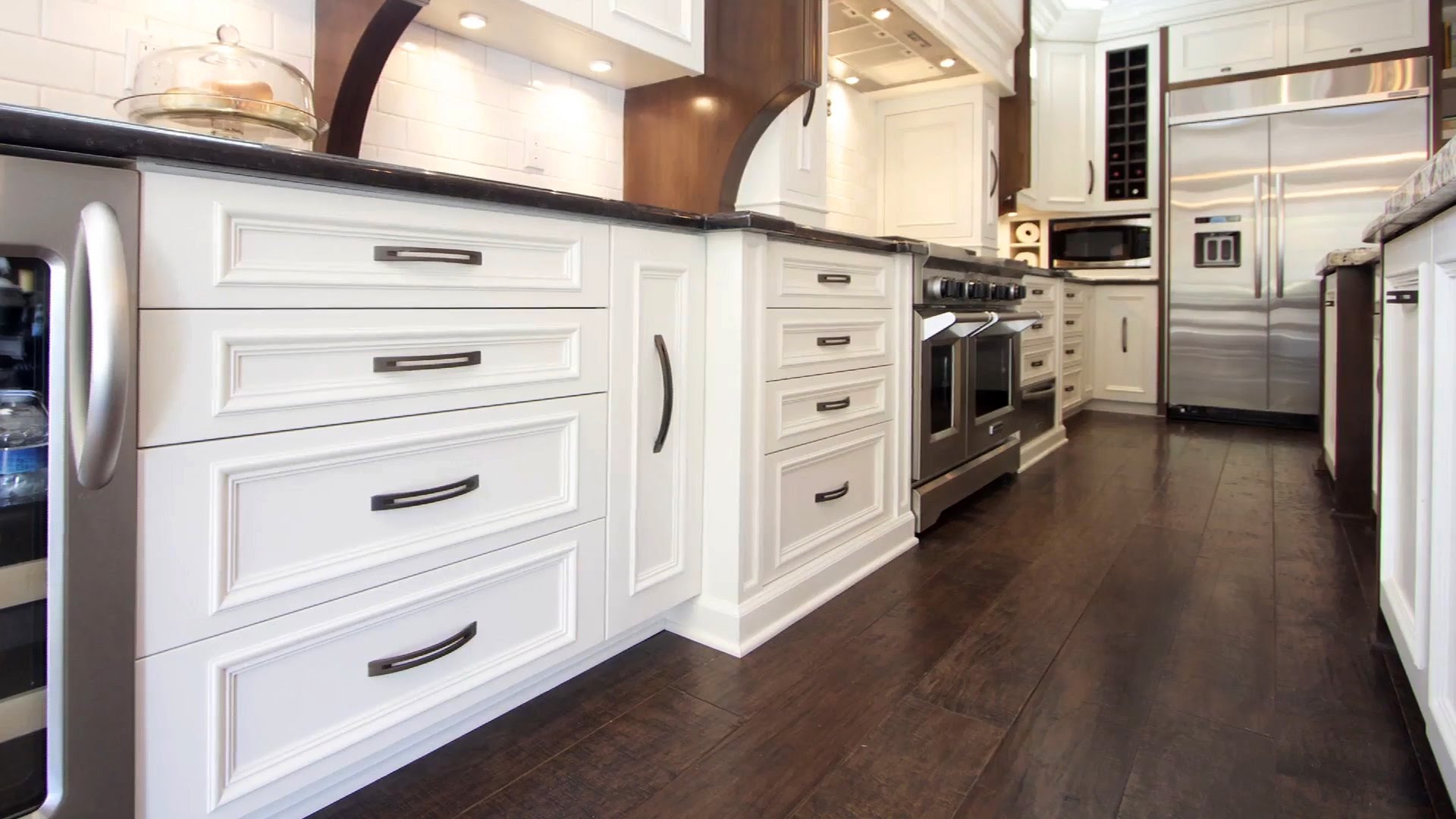 Una cocina blanca o beige claro con suelo de madera oscuro a contraste