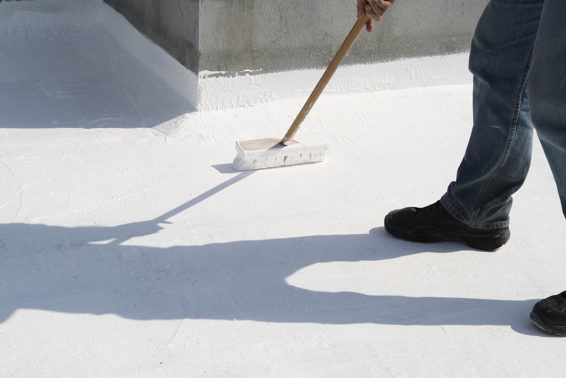 Como aislar un techo del calor_Un hombre aplicando pintura blanca comun como aislante termico al techo de una casa