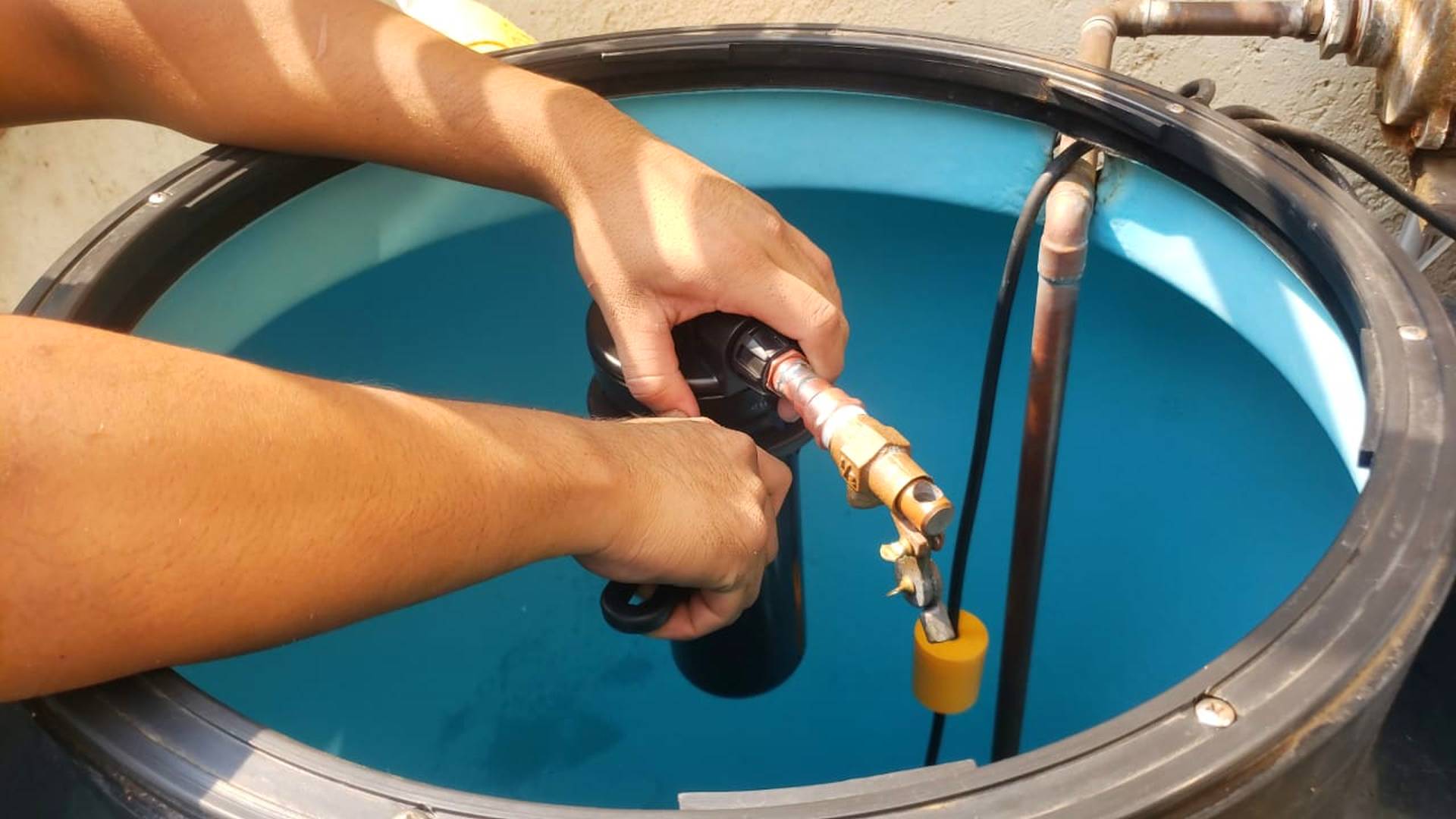 Una persona instalando un filtro en la entrada de agua de un tinaco domestico