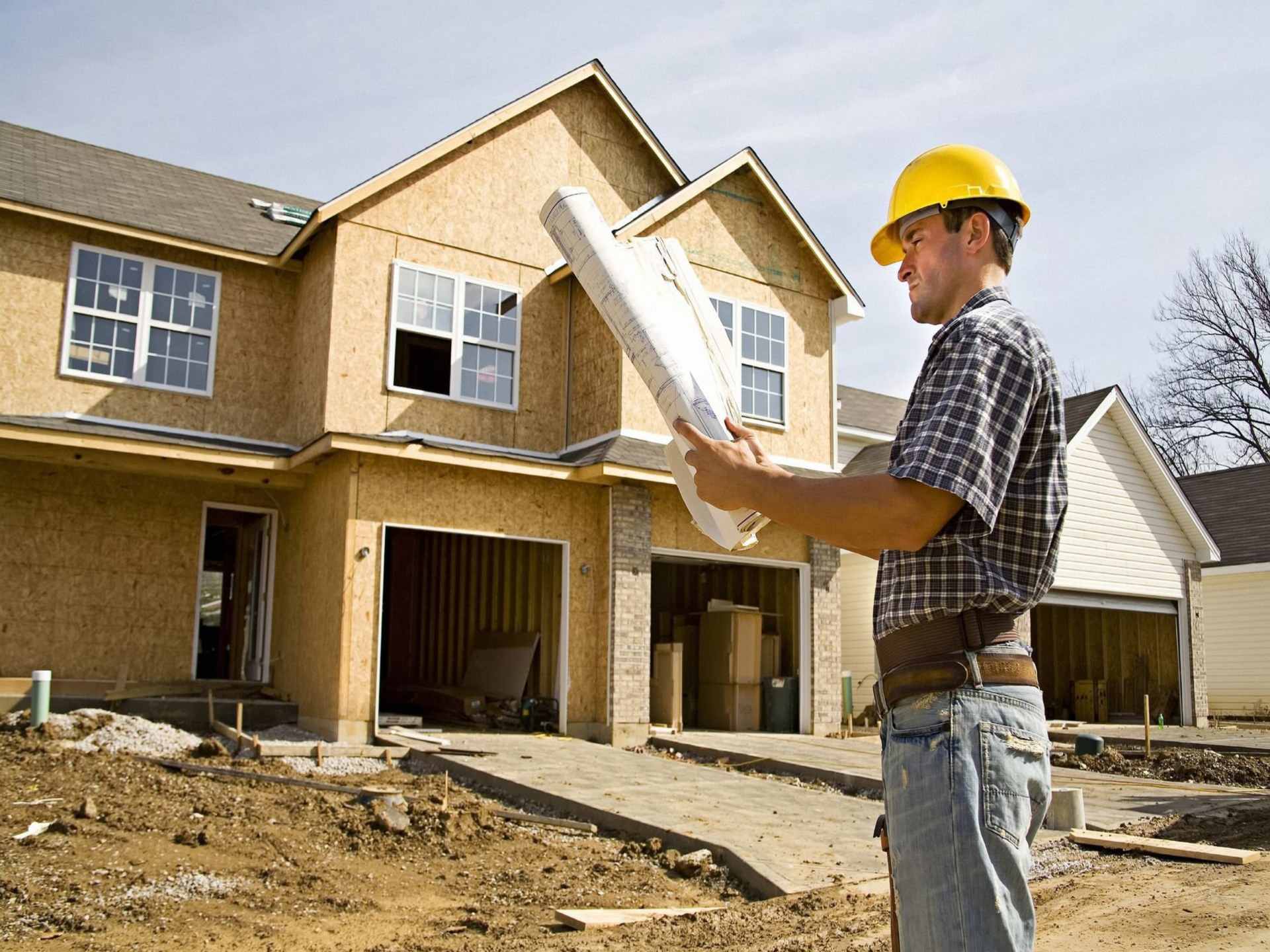 04 Un constructor analizando los planos de una casa en construccion_Punto de vista exterior con contrapiso en el garaje
